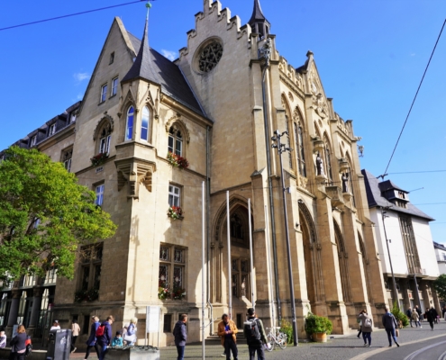 Rathaus von Erfurt Das historische Rathaus von Erfurt steht zentral auf dem Fischmarkt. Das beige-braune Gebäude hat einen neugothischen Stil mit vier massiven Säulen am Eingang.