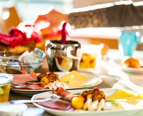 Frühstück Ein reichhaltig gedeckter Frühstückstisch mit: Wurst, Käse, Obst, Marmelade, Nutella, Brötchen, Croissants, Obstsalat, Kaffee und weiteren Getränken.
